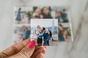 Hand holding a small photo print of a family with a cityscape background
