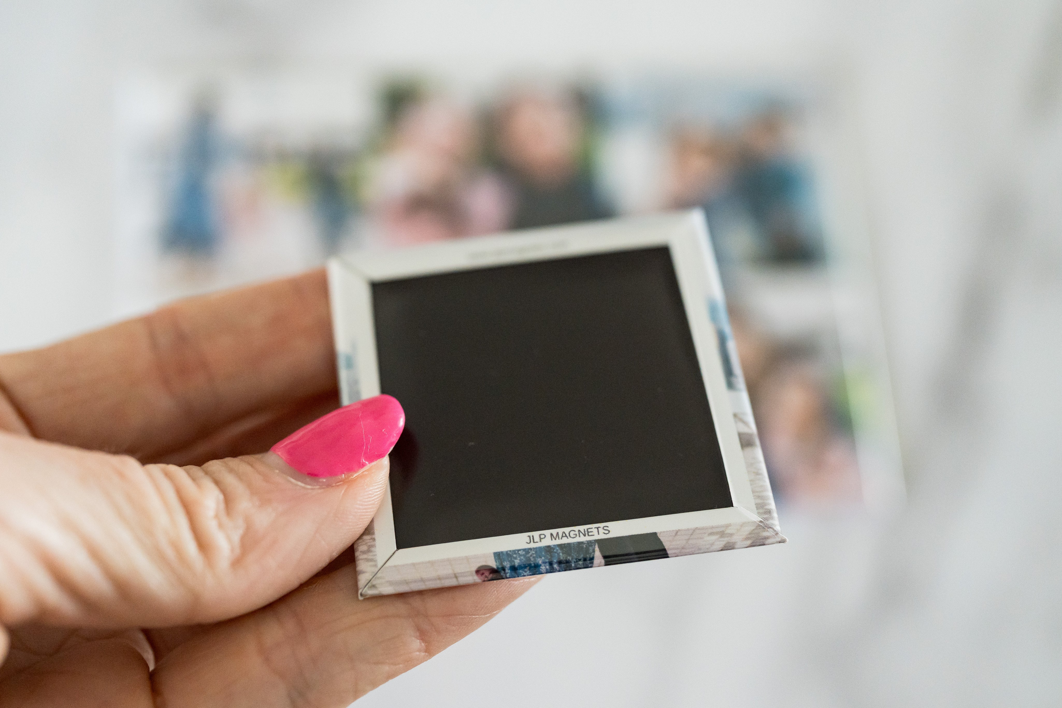 Hand holding a small electronic device with a blurred background